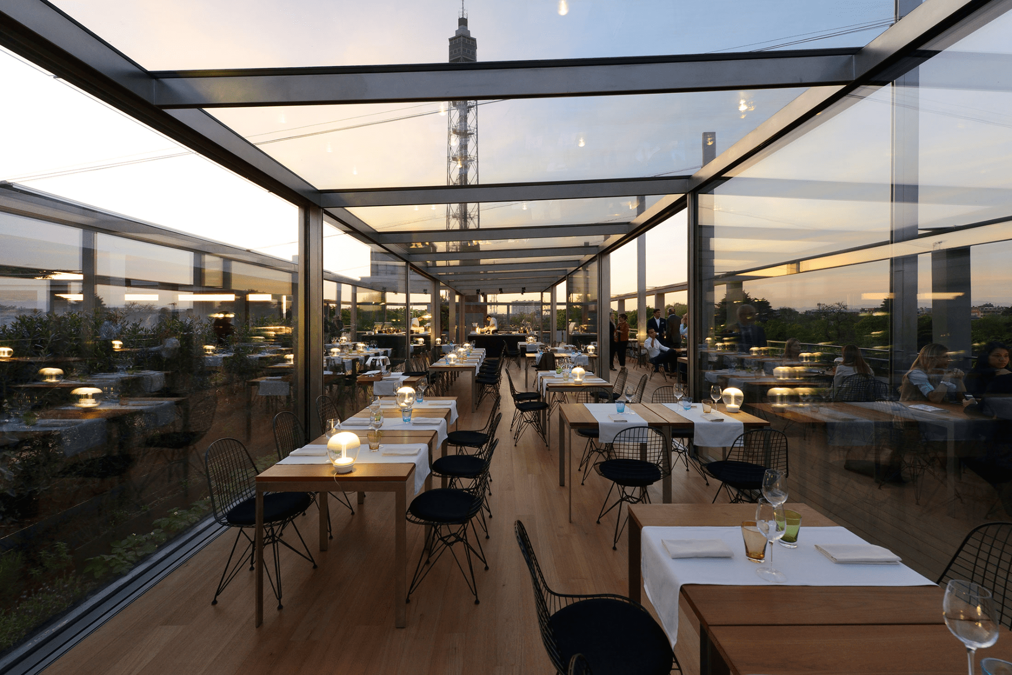 Terrazza al tramonto con tavoli apparecchiati per aperitivo a Milano