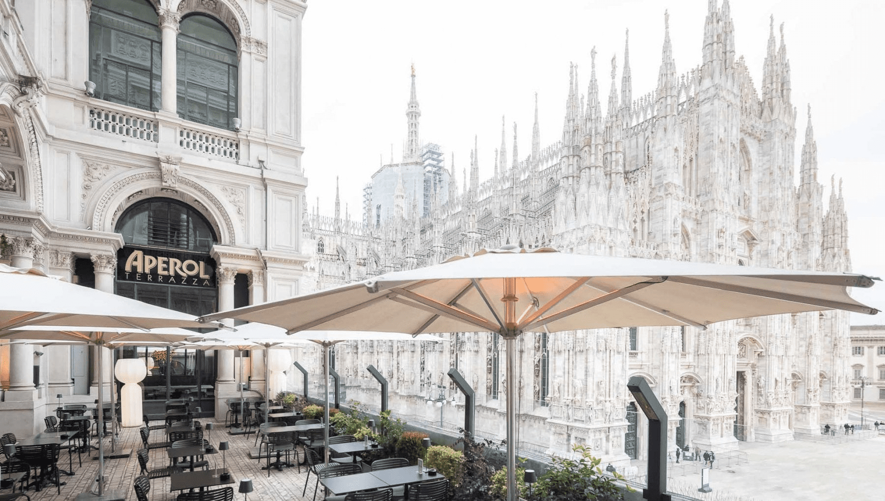 Terrazza al tramonto con tavoli apparecchiati per aperitivo a Milano 