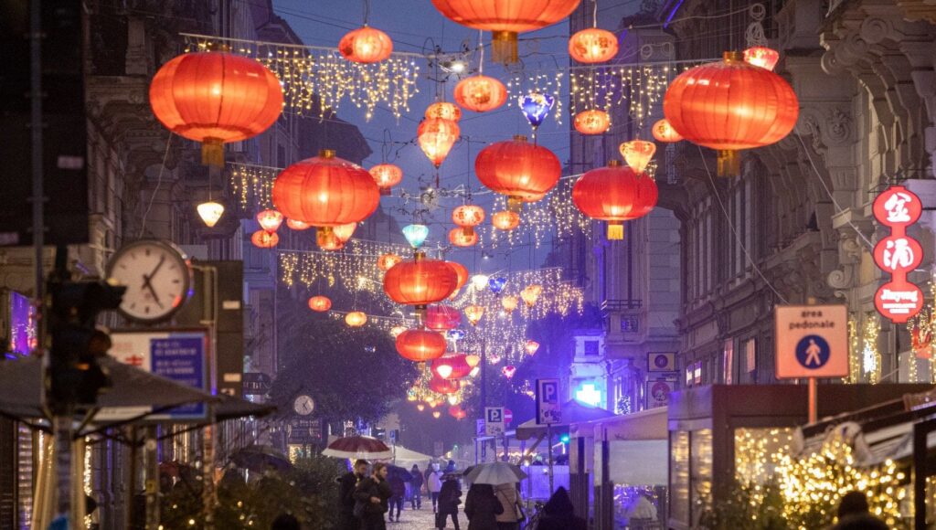 Foto di Via Paolo Sarpi illuminata dalle lanterne cinesi di notte, con la pioggia.