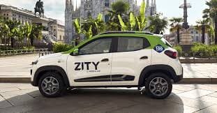 Macchina con logo Zity sullo sportello sinistro, parcheggiata con il Duomo di Milano sullo sfondo.