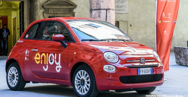 Fiat 500 rossa parcheggiata, con logo Enjoy sullo sportello destro.
