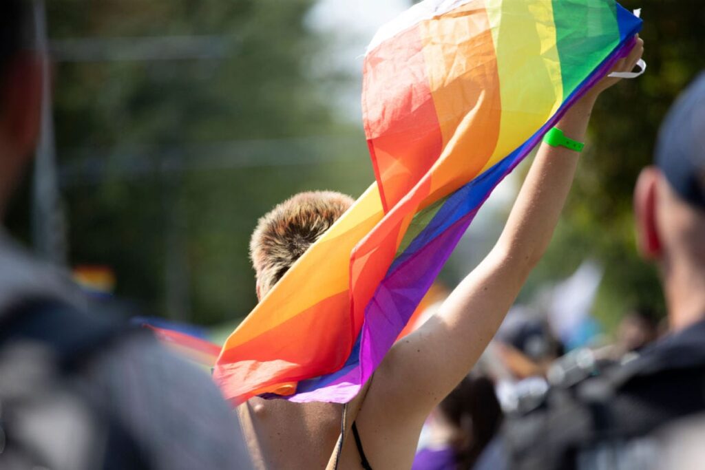  una persona sventola la bandiera arcobaleno in strada